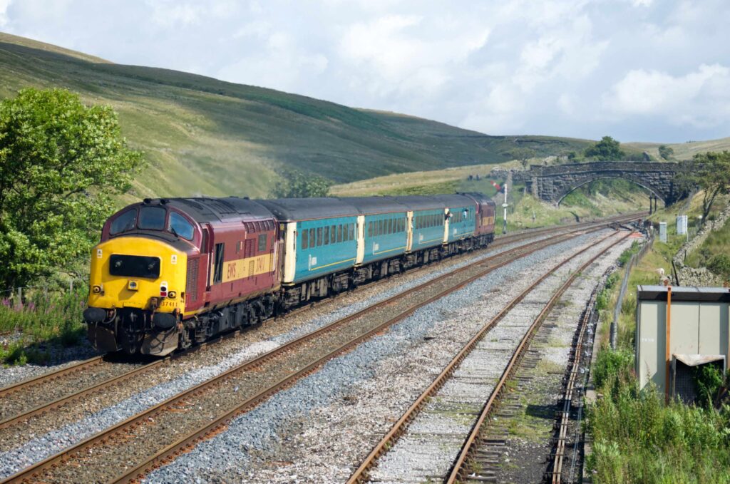 Two Class 37 diesel locomotives head north from Blea Moor signalbox with an Arriva passenger train for Carlisle.