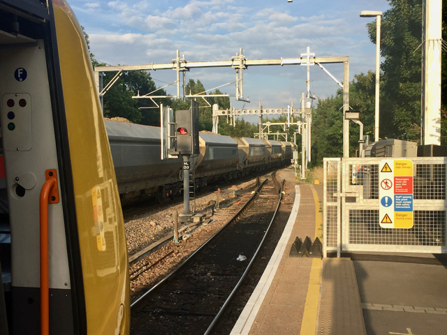 A train of freight wagons passes a passenger train at Gospel Oak station in North London.
